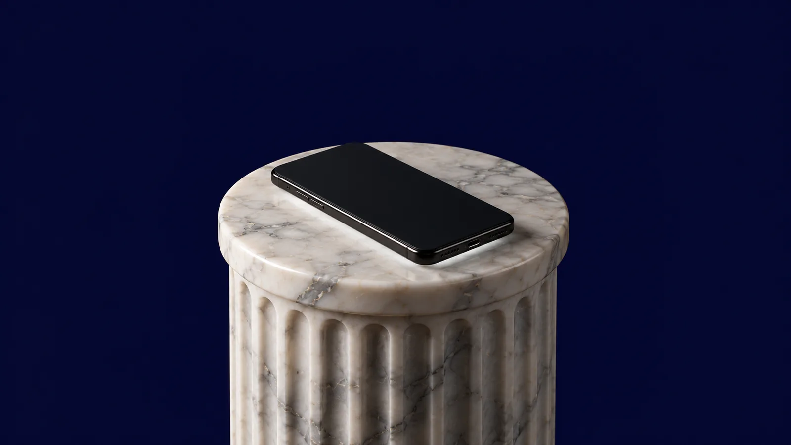 Colonna scanalata in marmo con uno smartphone nero spento sopra, fondo blu notte