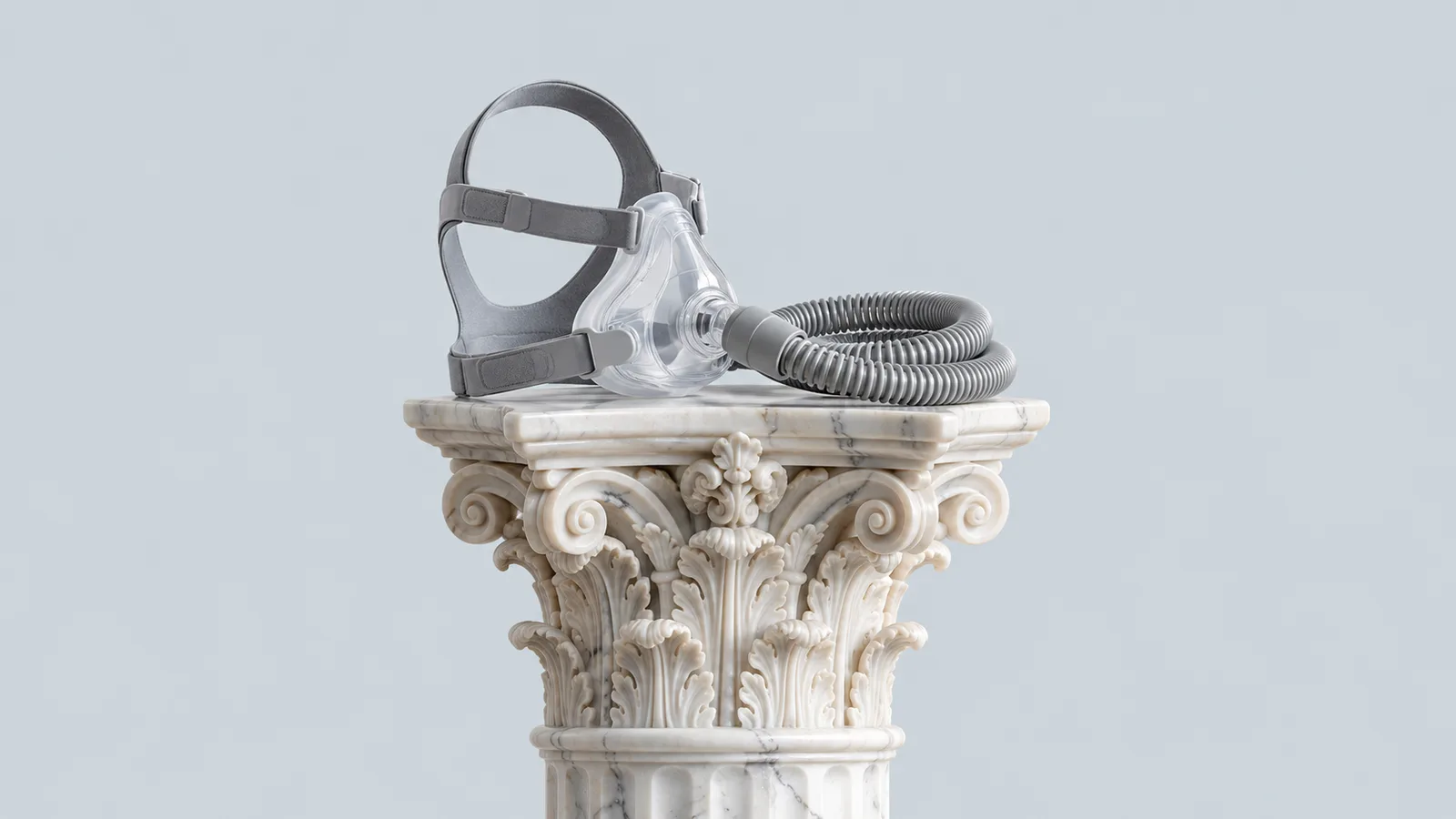 Capitello corinzio in marmo con sopra una maschera CPAP e il suo tubo arrotolato, fondo grigio perla
